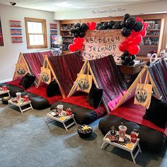 tents set up in the middle of a room with red and black decorations on them