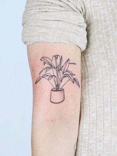 a woman's arm with a small potted plant tattoo on the left forearm