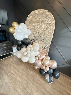 a table topped with balloons and a heart shaped balloon arch on top of a wooden table