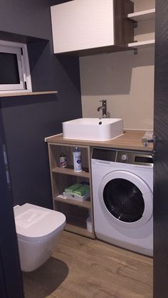 a washer and dryer in a bathroom with wood flooring on the walls