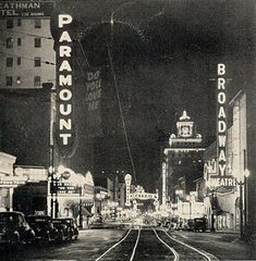 an old black and white photo of a train track in the middle of a city