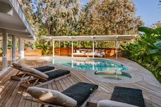 an outdoor deck with chaise lounge chairs next to a swimming pool in the backyard