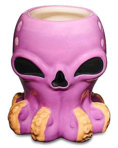 a purple alien mug sitting on top of a table