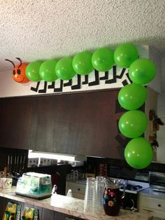 green balloons are hanging from the ceiling above a kitchen counter with an orange pumpkin on it