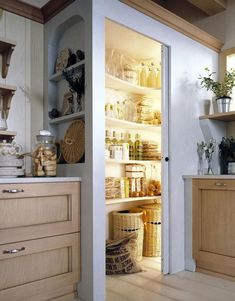 an open pantry door in a kitchen with lots of food on the shelves and baskets