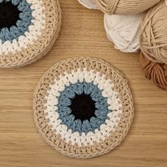 two crocheted baskets with balls of yarn next to them on a wooden surface