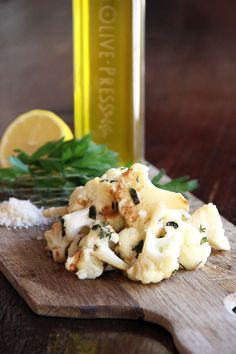 a wooden cutting board topped with cauliflower next to a bottle of olive oil