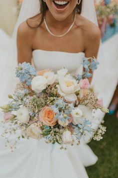 a woman in a wedding dress holding a bouquet of flowers and smiling at the camera