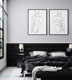 two black and white paintings hang above a bed