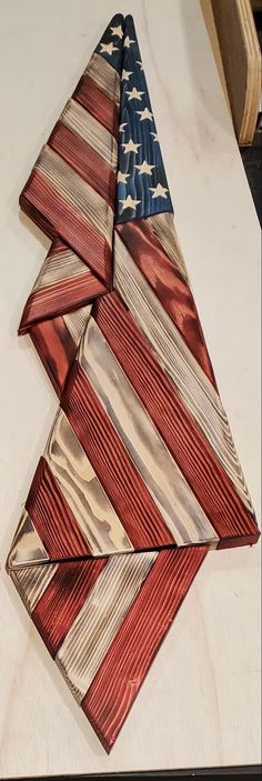 an american flag folded on top of a wooden cutting board next to a knife and fork