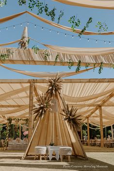 an outdoor wedding setup with tables and chairs under the canopy, surrounded by greenery