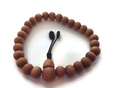 "This is a natural Tibetan sandalwood beads stretch wrist mala bracelet in the traditional japa mala style. Length of the bracelet is about 7-8\" and the bead size is about 7-8mm. The beads are strung on a durable elastic cord. Accented by a black tassel, you'll enjoy the natural fragrance of these high-quality sandalwood beads, creating a natural harmony, relaxation, and calm about you. In India and Tibet, sandalwood is given divine status and is thus very commonly used in mala beads. The fragr Brown Rosary Bracelet For Meditation, Brown Rosary Bracelet With 8mm Beads For Meditation, Wooden Beads Rosary Bracelet For Meditation, Meditation Rosary Bracelet With Wooden Beads, Spiritual Wooden Beads Stretch Bracelet For Meditation, Spiritual Stretch Bracelet With Wooden Beads For Meditation, Traditional Adjustable Wooden Beads Stretch Bracelet, Adjustable Wooden Beaded Bracelets With 8mm Beads, Adjustable Wooden Beaded Bracelet With 8mm Beads