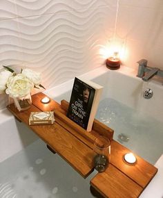 a bathtub with candles and a book on it