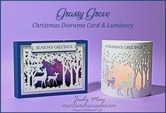 two christmas cards with deer and trees cut out of paper on purple background, one is white and the other has blue trim