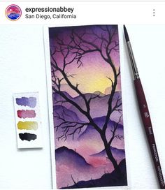 a watercolor painting of a tree with mountains in the background and paintbrush next to it