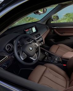 the interior of a bmw vehicle with brown leather seats and dashboard controls, including an electronic display