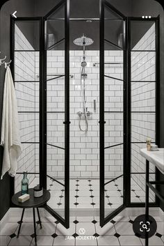 a black and white tiled bathroom with glass shower stall, pedestal sink, and standup shower