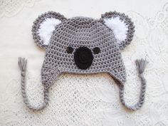 a crocheted hat with a koala bear on the front and ear flaps