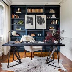 an office with black bookshelves and white rug