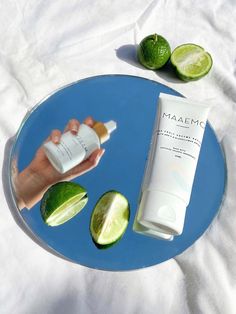 a person holding a tube of sunscreen and some limes on a blue plate