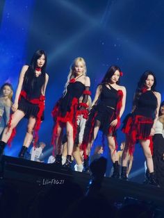 girls'generation performing on stage at an event with their red and black dresses flowing down