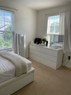 a bedroom with white furniture and large windows