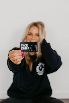 a woman sitting on the floor holding up a sign that says macie lensen