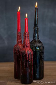 two wine bottles with candles in them sitting on a table