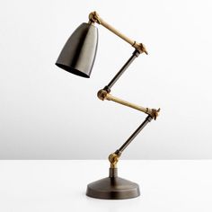 a desk lamp with two arms and a metal shade on the top, sitting on a white surface