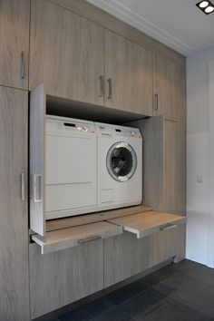 a washer and dryer sitting in the middle of a room with wooden cabinets