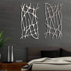 two metal art pieces on the wall above a bed in a room with grey walls