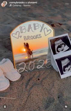 a baby's booties are laying on the sand next to a photo frame