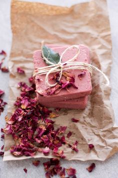 two pieces of pink soap sitting next to each other on top of brown paper with flowers