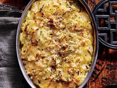 a casserole dish with cheese and herbs in it on a wooden table next to a cast iron grate