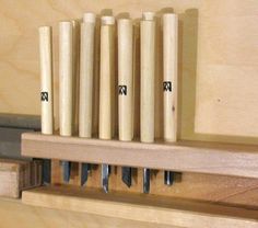 a set of wood chisels sitting on top of a wooden shelf