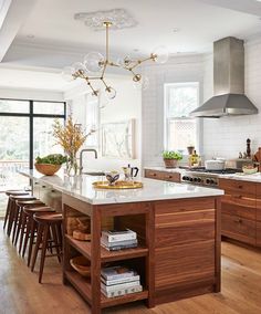 a kitchen with wooden floors and an island in front of a stove top oven surrounded by chairs