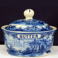 a blue and white tureen with the word butter on it's lid sitting on a table