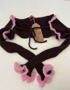 a knitted scarf with pink and black trims on the bottom, attached to a string