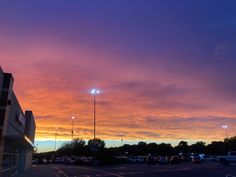 a parking lot filled with lots of cars under a colorful sky