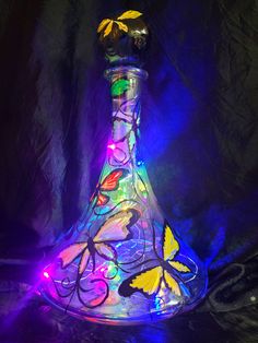 a glass vase with colorful lights in the shape of flowers and butterflies on it's side