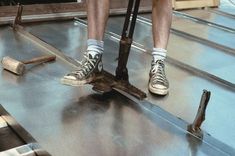 a man standing on top of a metal floor next to a pair of shoes and hammers