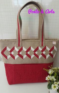 a red and white bag sitting on top of a table next to a vase with flowers