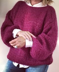 a woman wearing a purple sweater and jeans is posing for the camera with her hands on her hips