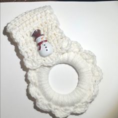 a white crocheted object with a snowman button on the front and bottom