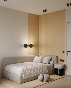 a white bed sitting on top of a wooden floor next to a wall mounted light