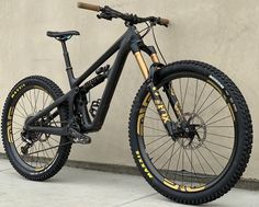 a black and gold mountain bike parked in front of a wall