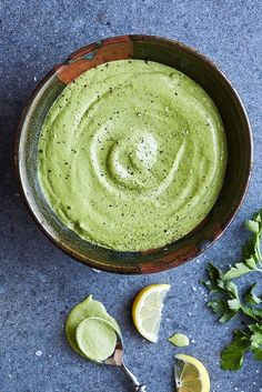 a bowl filled with avocado and garnish next to two lemon wedges