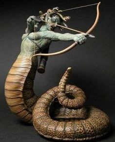 a statue of an animal with a bow and arrow in its mouth next to a snake