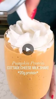 a person is holding a cup with whipped cream in it and the text pumpkin protein cottage cheese milkshake