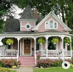 a pink and white house with flowers on the front porch